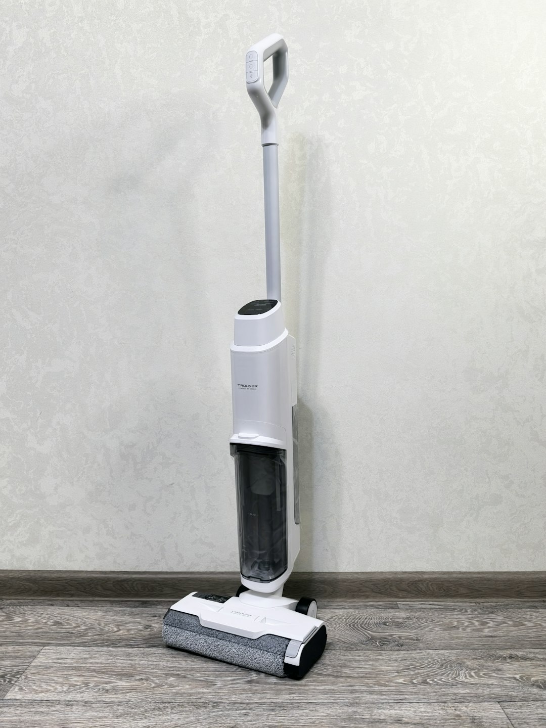 Aspirateur balai sans fil appuyé contre le mur d'un corridor lumineux